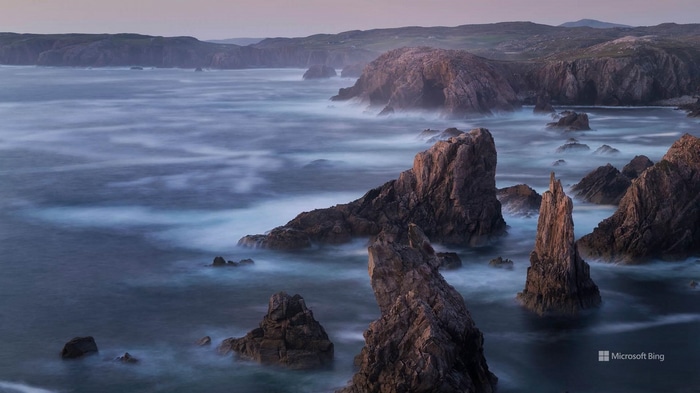 Rocky coastline with waves crashing at dusk
