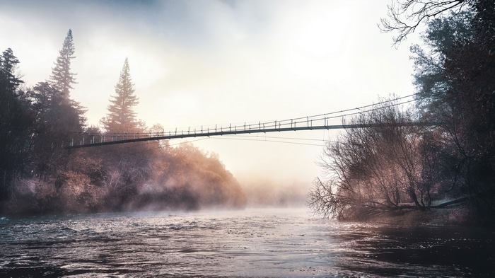 4K bridge over a misty river with trees