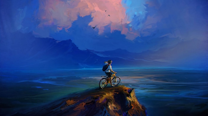 Man on bicycle on cliff overlooking ocean and mountains