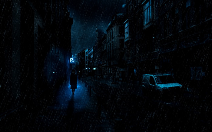 A lone figure walks down a dark, rainy street at night.