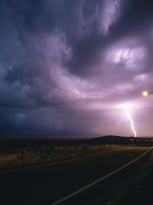 Lightning strikes over a desert road at night