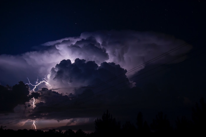 Lightning strikes through dark storm clouds at night