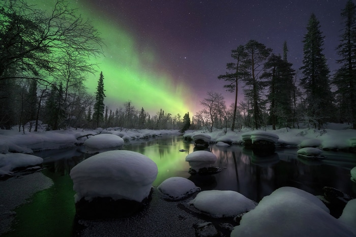 Aurora Borealis over a snowy river at night