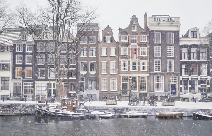 Amsterdam canal in winter with snow and boats