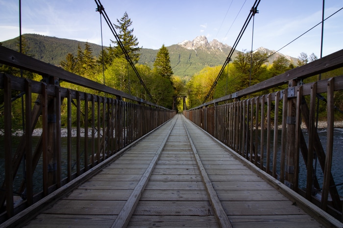 Wooden suspension bridge over a river with mountains
