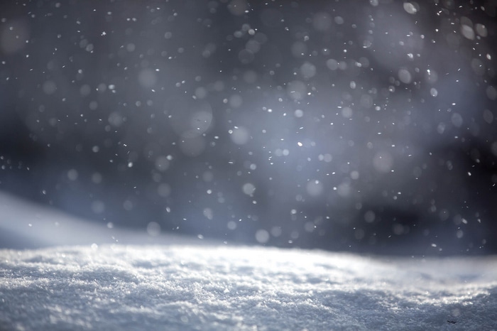 Snowflakes falling on a snowy ground in winter