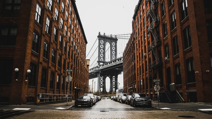 4K Manhattan Bridge between brick buildings in New York City