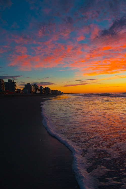 Beach apartments at sunset with colorful sky and ocean waves