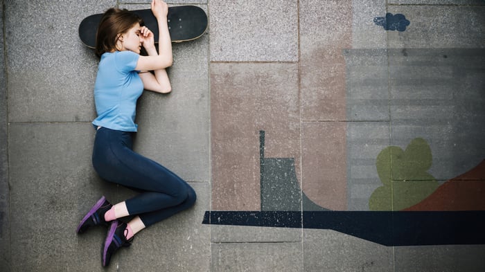 Girl sleeping on a skateboard on pavement