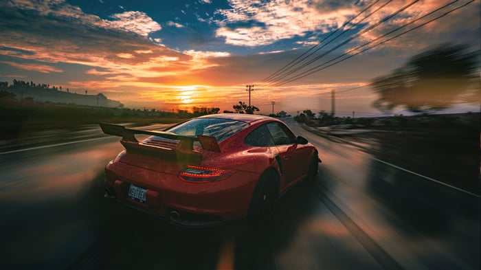 Red Porsche 911 GT2 RS driving at sunset