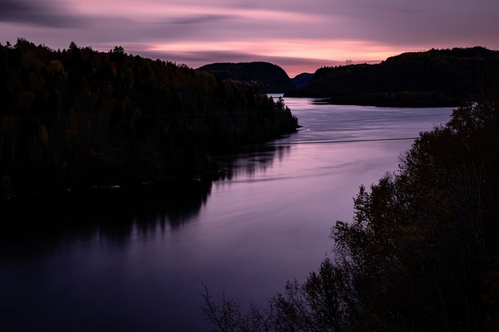Purple twilight over a calm lake and forested hills