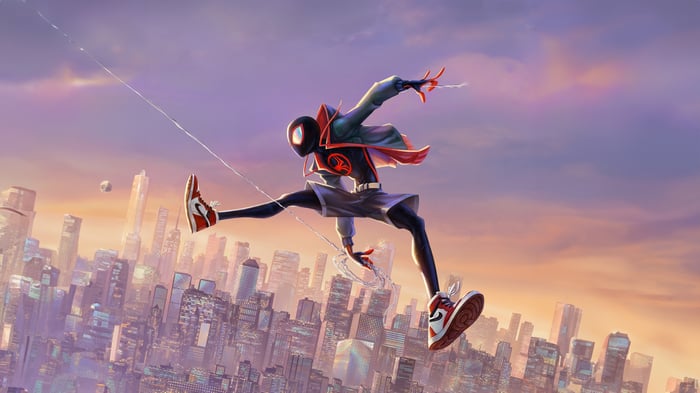 Spider-Man swinging over a city at sunset