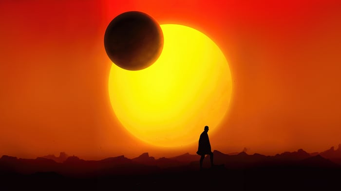 Silhouette of a person walking under a large sun and moon.