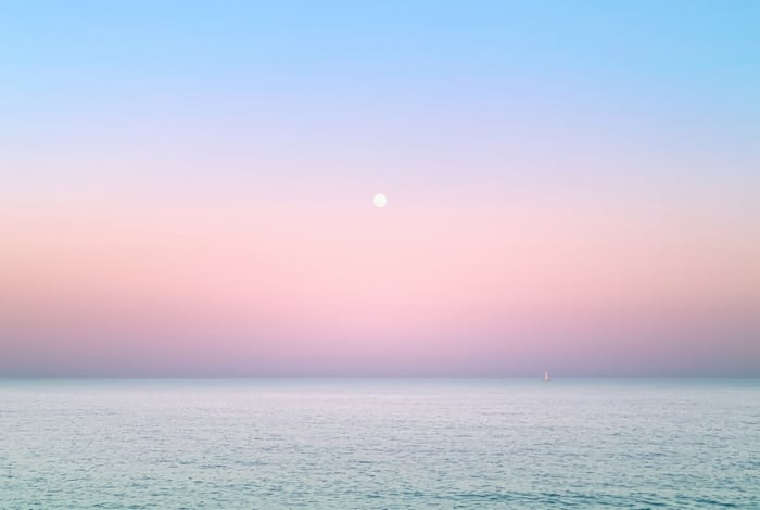 Moonlit Ocean at Dawn with a Distant Sailboat