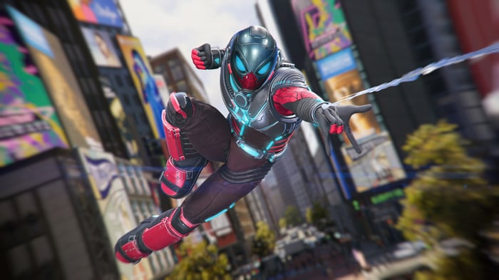 Spider-Man in a futuristic suit swings through a city