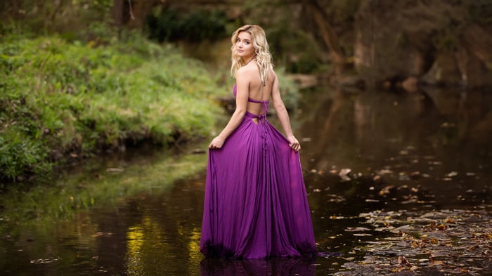 Woman in purple dress by a stream