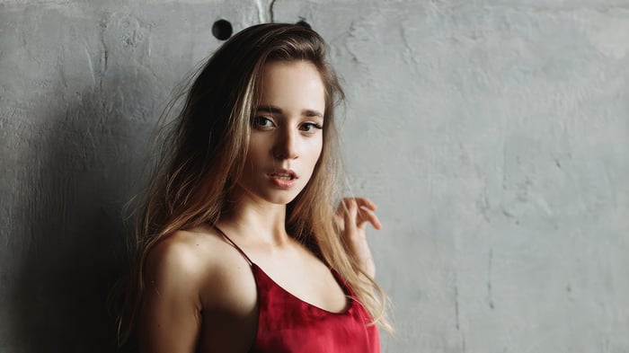 Blonde woman in a red dress against a concrete wall