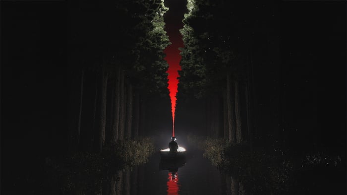 A person in a boat on a dark lake with a red light beam