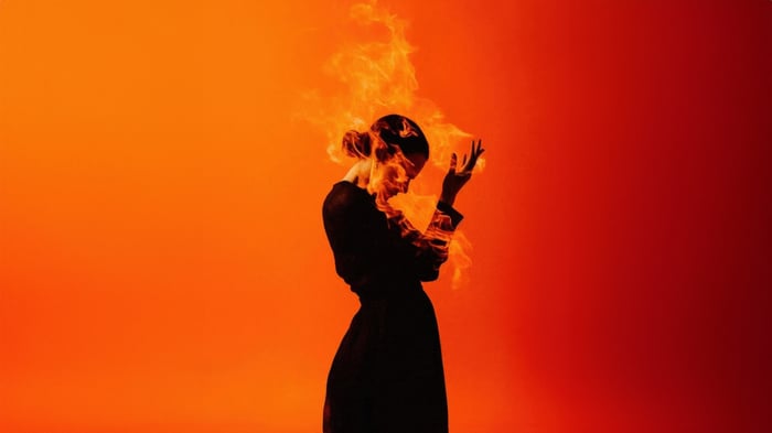 Woman engulfed in flames against orange background