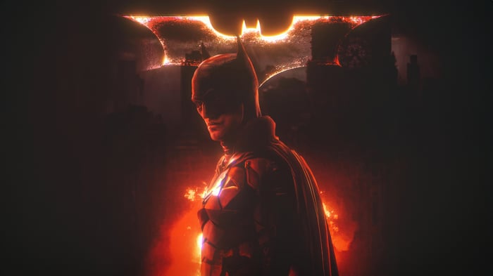 The Batman in front of a fiery bat symbol