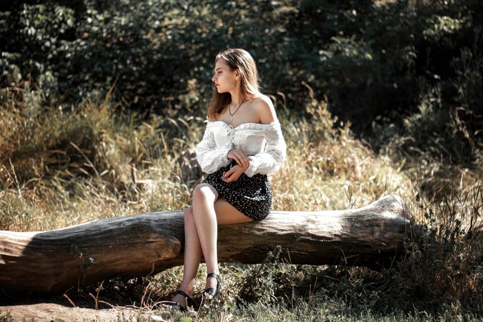 Girl Sitting on a Log in a Forest