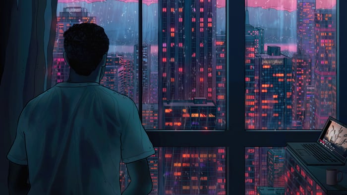 Man looking out window at rainy city skyline