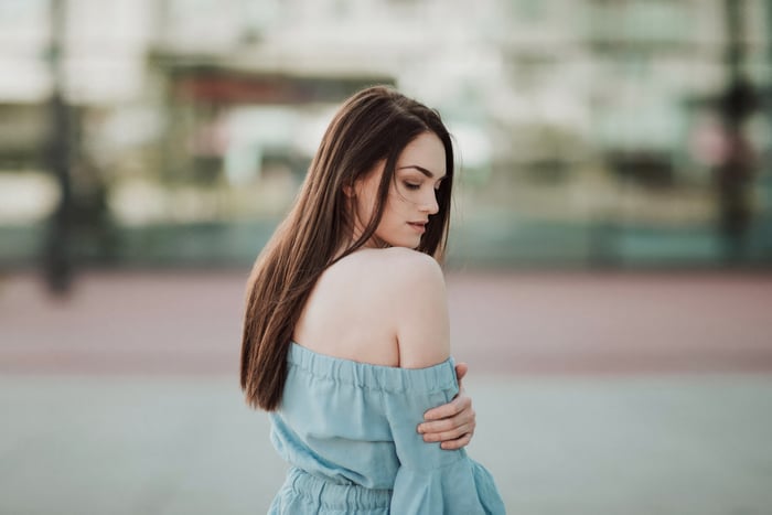 Woman in a blue off-the-shoulder dress looking back
