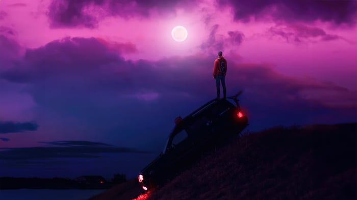 Man Standing on Car Under Pink Moon