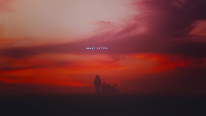Silhouette of a person and motorcycle against a sunset sky with text