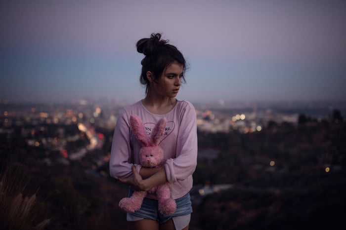 Girl holding a pink bunny with city lights in the background
