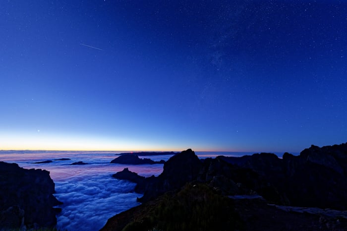 Mountain heights above clouds under starry sky