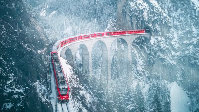 Red train on a snowy viaduct in Switzerland