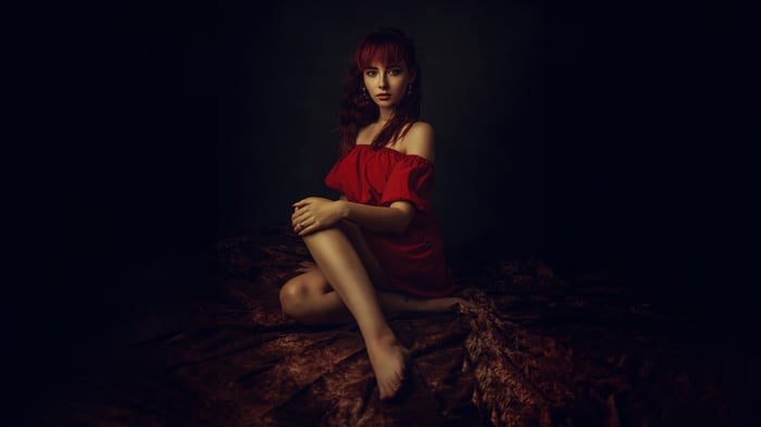 Woman in red dress sitting on velvet fabric