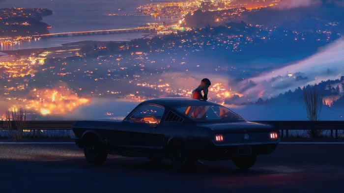 Person on a classic car overlooking a city at night