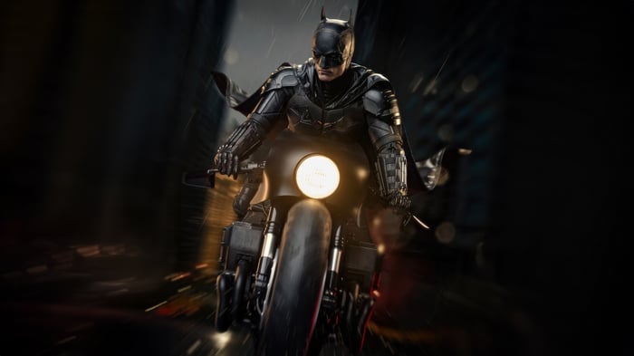 The Batman rides his Batcycle through a dark city