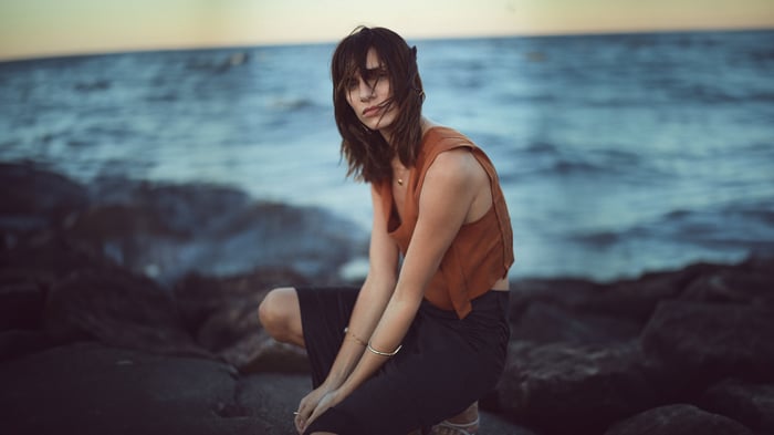 Woman crouching on rocks by the sea