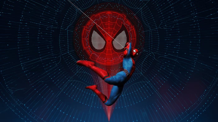 Spider-Man swinging in front of a spider emblem