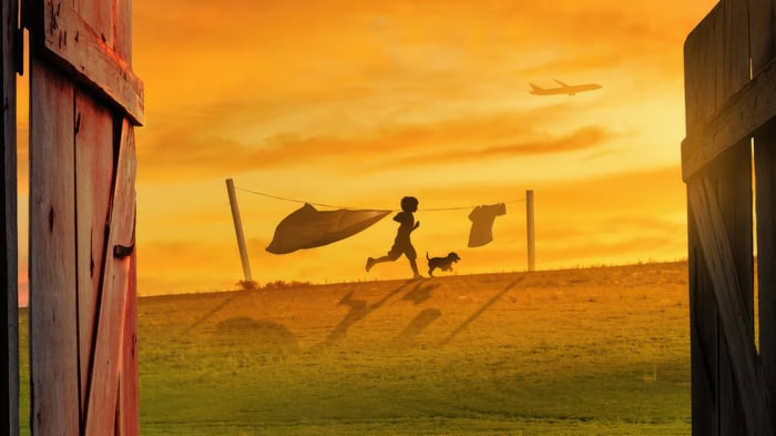Child and dog run past clothesline at sunset