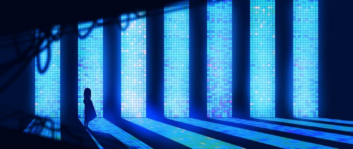 Girl standing in a room with glowing blue screens