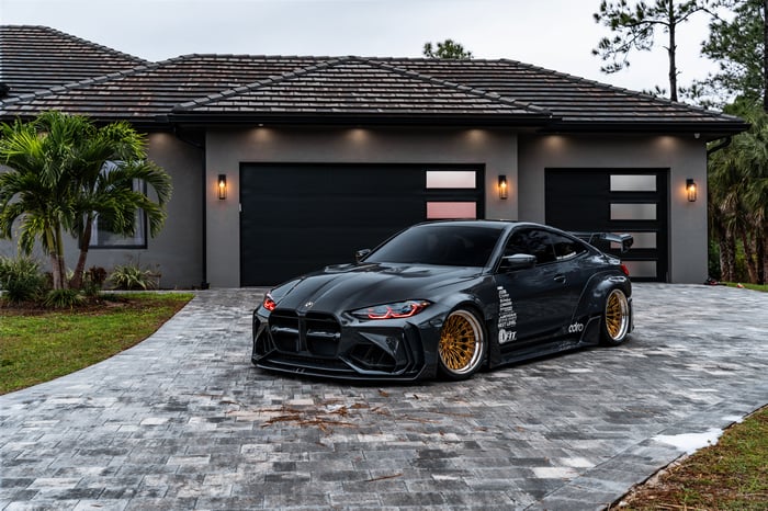 Widebody BMW M4 parked in front of a modern house