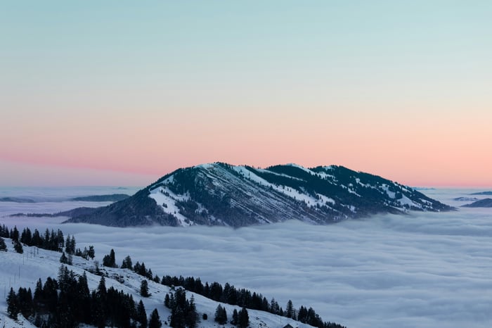Snow-covered mountain range above clouds at sunrise