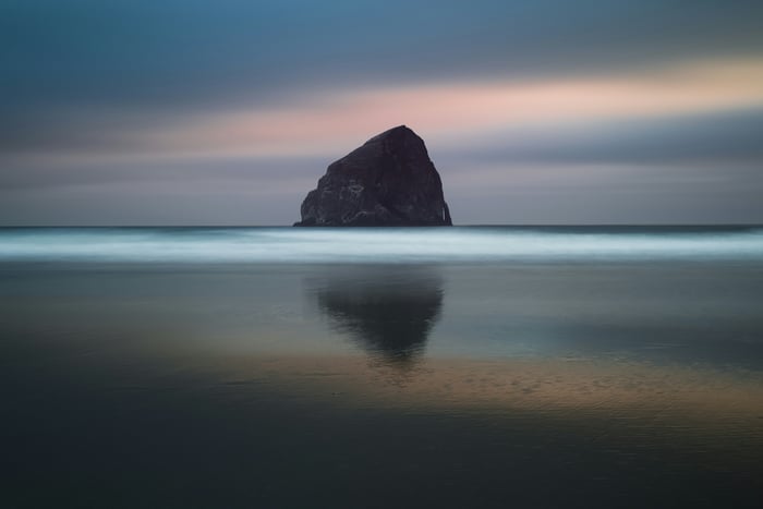 Large rock formation in the ocean at dusk