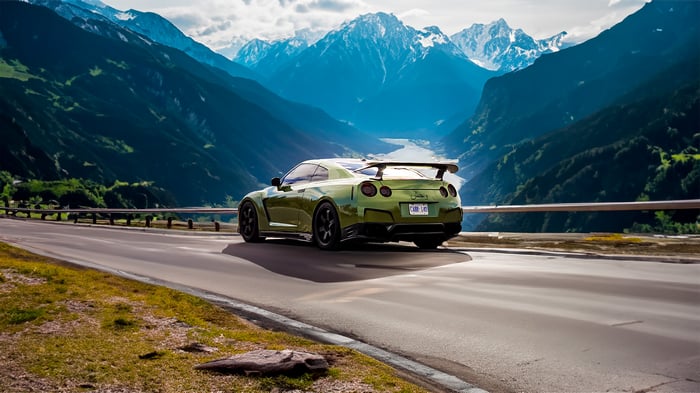 Green Nissan GTR 35 driving on a mountain road