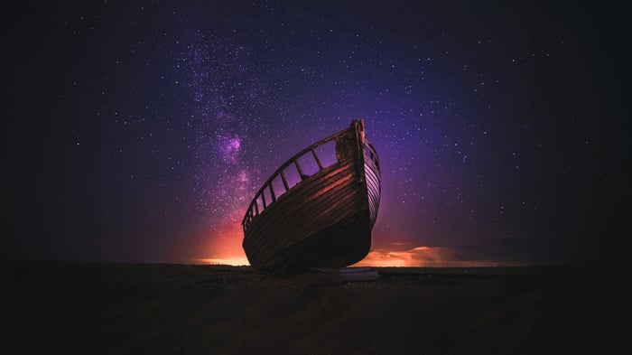 Wooden boat under a starry galaxy sky