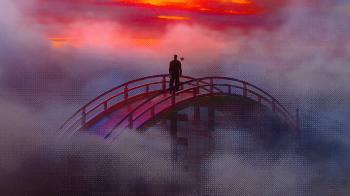 Man on a bridge in the clouds at sunset