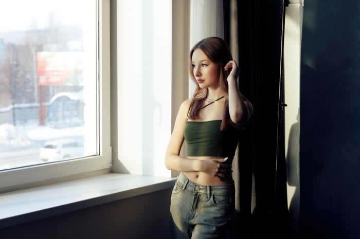 Girl in crop top and jeans by window