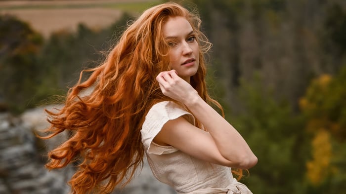 Red-haired woman with long wavy hair in the air