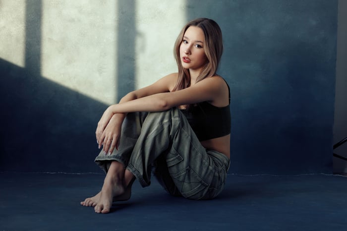 Blonde girl sitting indoors with legs crossed