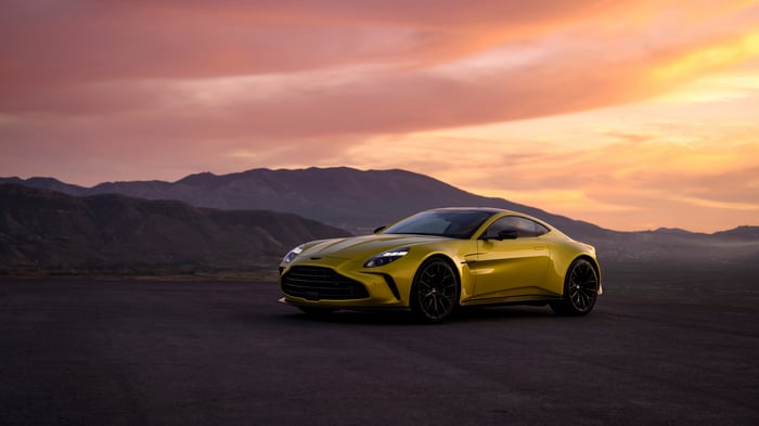 Yellow Aston Martin Vantage 2024 on a road at sunset
