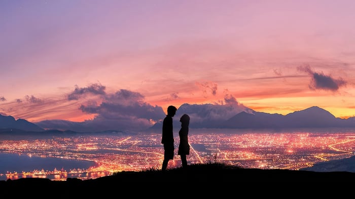 Couple silhouetted against a city skyline at sunset